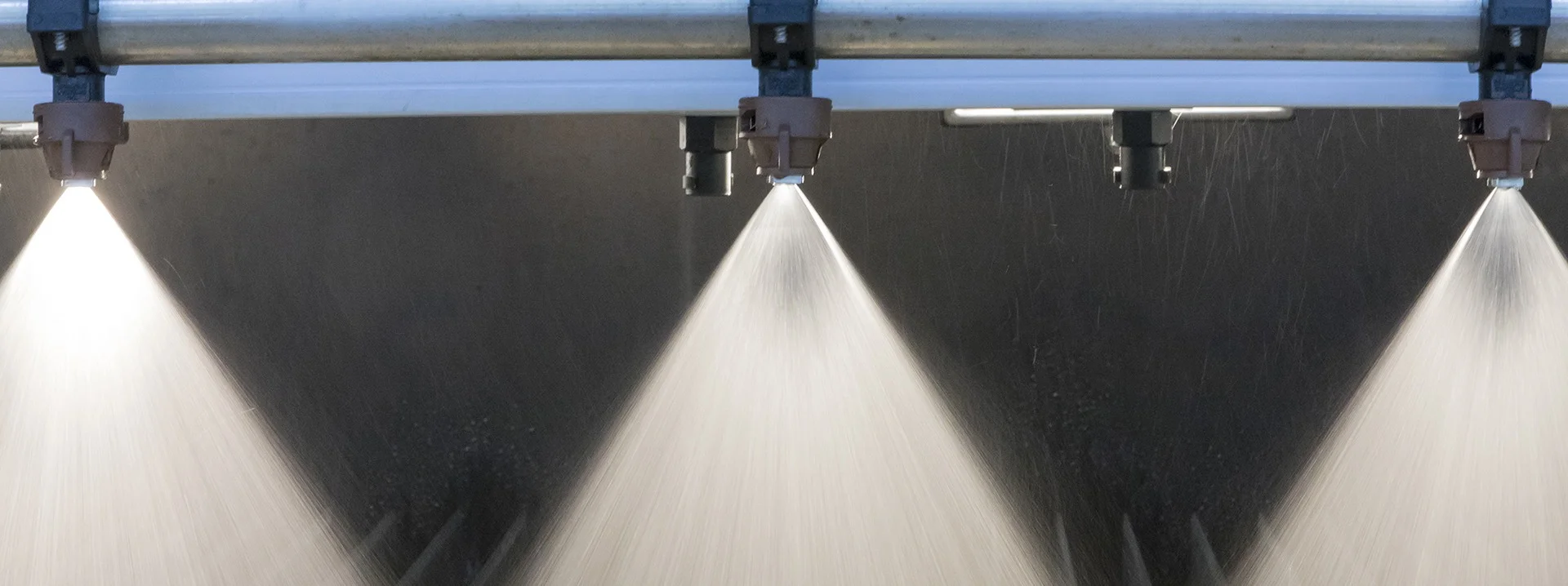 Industrial spray nozzle header with precision spray nozzles in active production